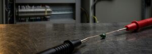 NTC thermistor temperature sensor being tested with multimeter probes on an industrial workbench