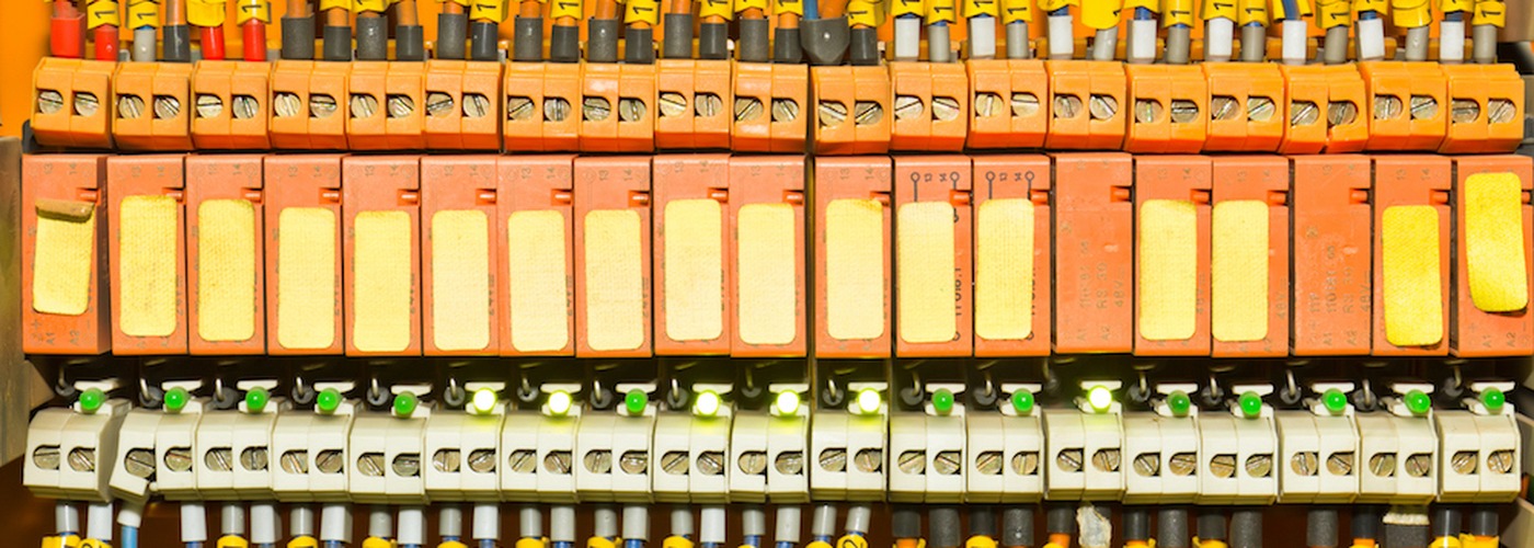 Row of screw and plug-in terminal blocks wiring electrical connections on an industrial panel